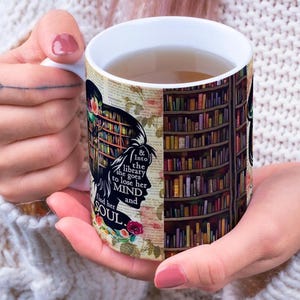 May include: White ceramic mug with a library theme. The mug features a silhouette of a woman with a bookshelf design and the text "& into the library she goes to lose her mind and find her soul."