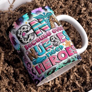 Può includere: Tazza da caffè in ceramica bianca con un design colorato che presenta il testo "CNA because even nurses need heroes". Il design include una varietà di motivi, tra cui la stampa leopardata, i pois e elementi floreali.