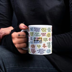 May include: White ceramic mug with a colorful design featuring the text "My Daily Bible Affirmations". The mug is filled with bible verses and affirmations.