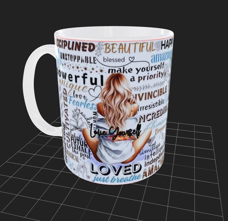 Puede incluir: Taza de cer&aacute;mica blanca con una mujer de pelo rubio, sentada de espaldas al espectador. La taza est&aacute; adornada con palabras inspiradoras como "Love Yourself", "Beautiful" y "Loved".