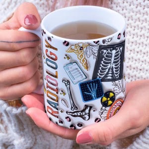 Könnte beinhalten: Ein Set aus drei Keramikbechern mit gesprenkelter, matter Oberfläche. Die Becher sind in den Farbtönen Creme, Hellgrau und Dunkelgrau gehalten. Jeder Becher hat ein schlichtes, minimalistisches Design und einen abgerundeten Griff.