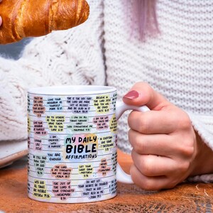 May include: White ceramic mug with a colorful design featuring bible verses and the text "My Daily Bible Affirmations".