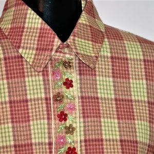 May include: A red and green plaid shirt with a floral embroidered trim down the front.