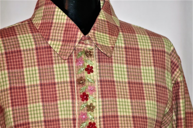 May include: A red and green plaid shirt with a floral embroidered trim down the front.