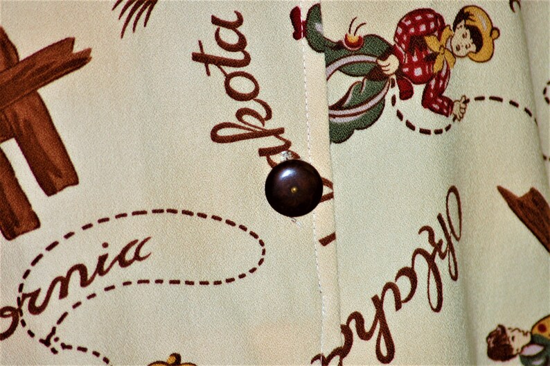 May include: A beige fabric with a brown button and a cartoon cowboy riding a horse. The fabric has the words "California" and "La Jolla" printed on it.