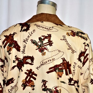 May include: A cream-colored button-up shirt with a brown suede collar. The shirt features a repeating pattern of cowboys riding horses and roping, with the names of states including "Montana", "Texas", "New Mexico", and "Nebraska" written in a cursive font.