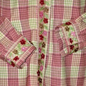 May include: A pink and green plaid shirt with a floral embroidered trim along the front and cuffs.