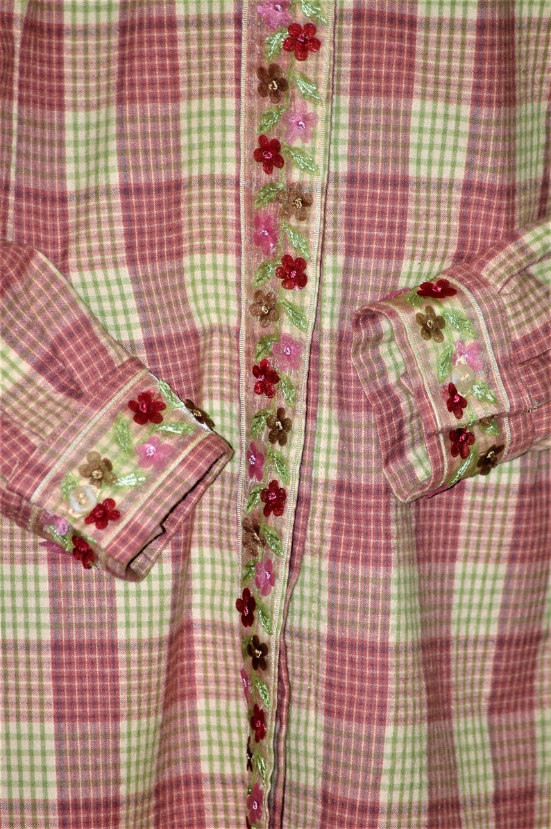 May include: A pink and green plaid shirt with a floral embroidered trim along the front and cuffs.