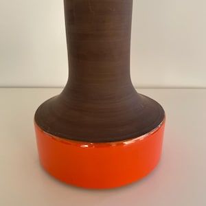 May include: A brown ceramic vase with a flared base and a bright orange rim.
