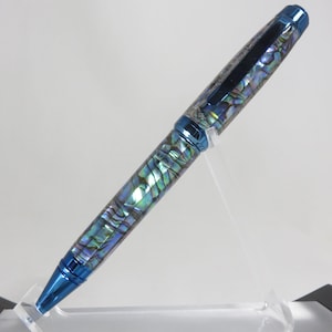 May include: A ballpoint pen featuring a barrel and cap inlaid with iridescent abalone shell segments displaying shades of blue, green, and purple. The pen includes polished metallic blue components at the tip, center, and top, with a matching blue clip.