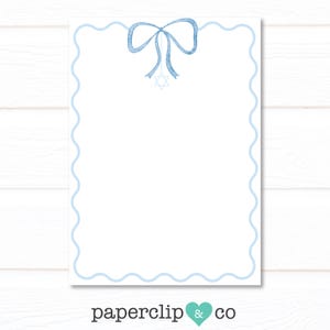 May include: A white stationery sheet with a light blue scalloped border and a matching bow and Star of David illustration at the top. The stationery has the text "paperclip & co" at the bottom.