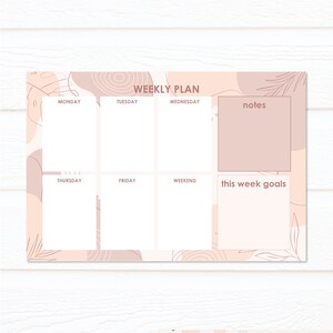 May include: A printable weekly planner with a pink and white color scheme. The planner has sections for Monday through Sunday, as well as a notes section and a section for this week's goals. The planner is decorated with abstract shapes and leaves.