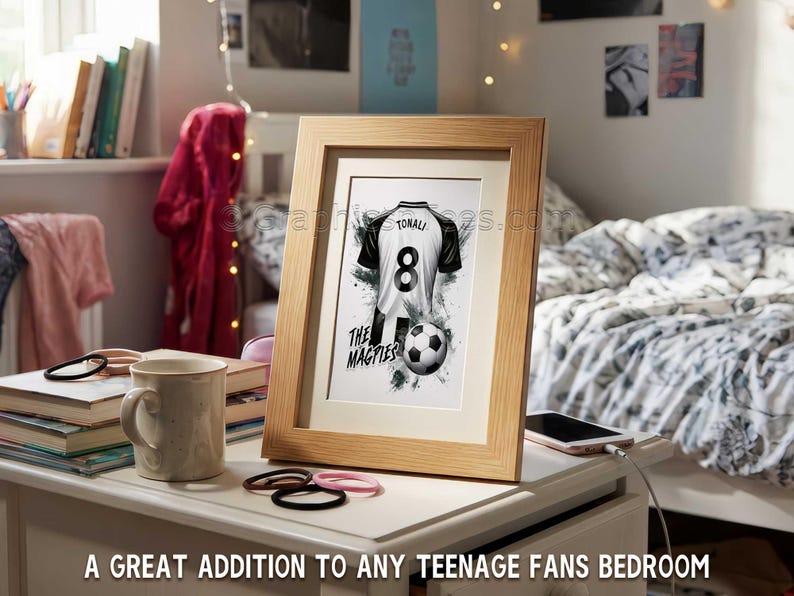 May include: Framed artwork featuring a black and white soccer jersey with the name "TONALI" and the number "8". A soccer ball is below the jersey. The text "THE MAGPIES" is also visible. The frame is light brown. The text at the bottom says "A GREAT ADDITION TO ANY TEENAGE FANS BEDROOM".