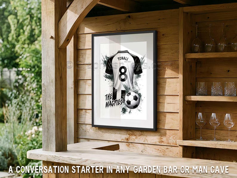 May include: Framed print of a black and white soccer jersey with the name "TONALI" and the number "8". A soccer ball and the words "THE MAGPIES" are also featured. The print is displayed on a wooden wall.