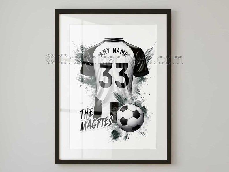 May include: Framed artwork featuring a black and white soccer jersey with the number 33 and the words "ANY NAME" above it. A soccer ball is positioned below the jersey, with the words "THE MAGPIES" beneath it. The background has a splash effect.