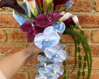 Ramo de flores de seda con calas azules, burdeos y blancas, orquídeas colgantes de anturio azul, amaranto verde y calas burdeos y blancas.