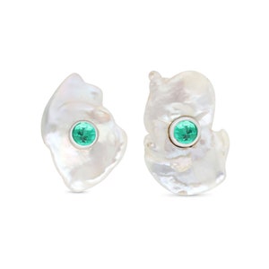 Puede incluir: Un par de pendientes de perlas blancas con detalles de piedras preciosas verdes. Los pendientes tienen una forma irregular y un aspecto natural y orgánico.