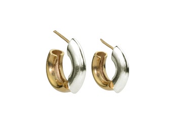 May include: A pair of hoop earrings with a gold and silver finish. The earrings are made of two half-circles that are joined together.