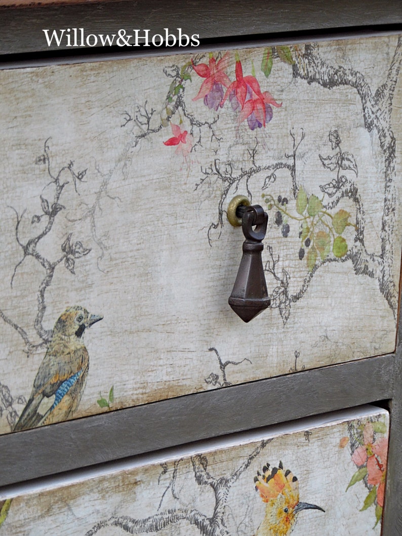 May include: A vintage-style dresser with two drawers, featuring a floral and bird design. The top drawer has a black metal knob and the text "Willow & Hobbs" is printed on the top.