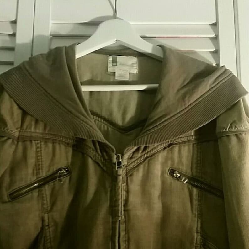 May include: A brown hooded jacket with a zipper closure and multiple pockets. The jacket has a corduroy-like texture and a wide collar.