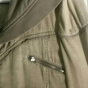 May include: A beige corduroy jacket with a zipper detail and a fold-over collar.
