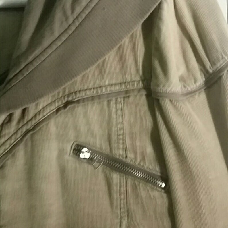 May include: A beige corduroy jacket with a zipper detail and a fold-over collar.