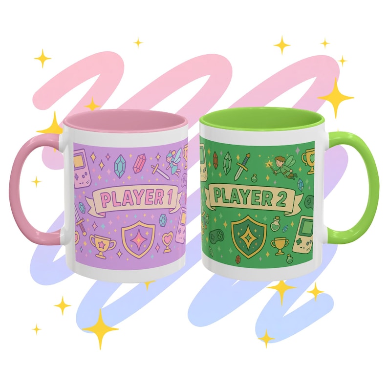 Op de afbeelding: Twee witte keramische mokken met kleurrijke ontwerpen. E&eacute;n mok heeft een roze binnenkant en oor, de andere heeft een groene binnenkant en oor. Elke mok heeft een banner met "PLAYER 1" en "PLAYER 2" en graphics met gaming-thema.