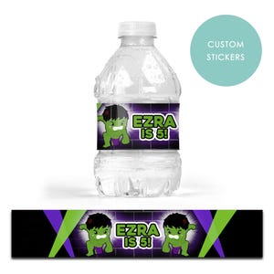 May include: A clear water bottle with a custom label featuring a green cartoon character and the text "Ezra is 5!". The label has a purple and green background. A matching label is at the bottom.