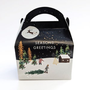 May include: A black and white gift box with a handle, featuring a winter scene with a deer, trees, and the text "SEASONS GREETINGS." The box has a snowy landscape with people and a cabin.
