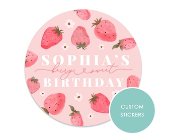 以下が含まれることがあります： ピンクの円形のステッカーで、イチゴの模様と「Sophia's berry sweet birthday」という白い文字が書かれています。ステッカーには、白い文字で「Custom Stickers」と書かれた薄い青色の円があります。