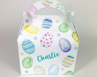 May include: White Easter-themed gift box with a handle, decorated with watercolor-style Easter eggs in various colors and patterns. The name "Charlie" is written in teal script on the front of the box. Perfect for Easter gifts or treats.