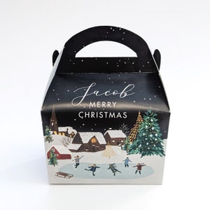 May include: A black gift box with a handle, featuring a winter village scene with ice skaters, snow-covered houses, and a Christmas tree. The text "Jacob Merry Christmas" is displayed on the front.