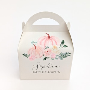Può includere: Una scatola regalo color crema con manico, decorata con zucche, rose e vegetazione ad acquerello. La scatola presenta il nome "Sophia" e il testo "HAPPY HALLOWEEN" in una scrittura elegante, perfetta per Halloween.