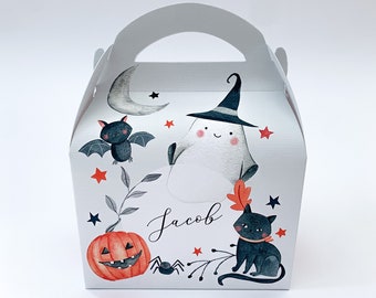 Può includere: Una scatola regalo bianca a tema Halloween, con manico, con illustrazioni di un fantasma con cappello da strega, un gatto nero, una zucca, un pipistrello, un ragno e una luna crescente. Il nome "Jacob" è scritto in corsivo.