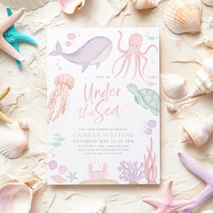 Puede incluir: Una invitación de baby shower rosa claro y azul con el texto "Join Us Under the Sea" e ilustraciones de criaturas marinas, incluyendo una ballena, un pulpo, una medusa, una tortuga y un cangrejo.