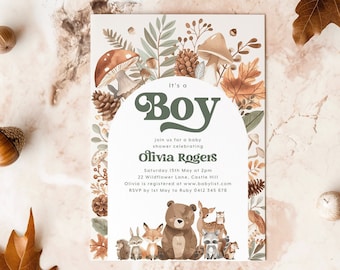 May include: It's a Boy baby shower invitation with a woodland theme. The invitation features a green and brown illustration of a forest with mushrooms, pine cones, and animals. The text "It's a Boy" is in a green circle with a brown outline. The invitation also includes the date, time, and location of the shower, as well as the name of the baby's mother, Olivia Rogers.