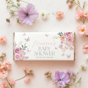 Pode incluir: Um embrulho de barra de chocolate branco com um design floral e borboletas. O texto no embrulho diz "Madison's Baby Shower Thanks for coming!"