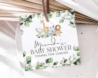 May include: A white baby shower favor tag with green eucalyptus leaves, a giraffe, a lion, an elephant, and a zebra. The text on the tag reads "Miranda's Baby Shower Thanks for Coming."