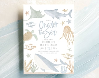 May include: A blue and white invitation card with the text "Oneder the Sea" and illustrations of sea creatures, including a shark, a turtle, a jellyfish, and a whale. The invitation is for a first birthday party.