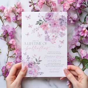 May include: A white invitation with a watercolor floral design in shades of purple and pink. The text reads "Here's to a lifetime of butterflies" and includes details for a bridal shower honoring Madison Hayes. The event is scheduled for October 25th at 2 PM at The Hayes Residence, 22 Citrus Lane, Castle Hill NSW. RSVP to Alana at 0412 345-678. The invitation also mentions that gifts are registered at Target and Amazon.