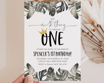 Puede incluir: Una invitación blanca con un diseño de hojas tropicales. El texto dice "Nuestro pequeño está cumpliendo UN AÑO" con una corona dorada sobre la palabra "UNO". La invitación también incluye detalles para una fiesta de cumpleaños, incluyendo la fecha, la hora, el lugar y la información de RSVP.