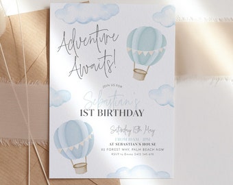 Puede incluir: Una tarjeta de invitación azul y blanca con un diseño de globo aerostático. El texto dice "¡La aventura te espera!" y "El 1er cumpleaños de Sebastián". La invitación incluye la fecha, la hora y el lugar de la fiesta.