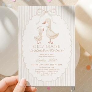 Puede incluir: Una tarjeta de invitación para baby shower con un diseño caprichoso que presenta dos gansos y el texto "SILLY GOOSE is almost on the loose!". La tarjeta está sostenida por una mano y rodeada de globos y confeti.