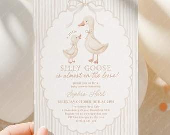 May include: A baby shower invitation card with a whimsical design featuring two geese and the text "SILLY GOOSE is almost on the loose!" The card is held by a hand and surrounded by balloons and confetti.