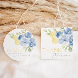 May include: Two round thank you tags with blue flowers, green leaves, and yellow lemons. The text on the tags reads "Thank you Love Charlotte".