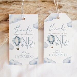 May include: Two blue and white thank you tags with a hot air balloon and clouds. The text on the tags reads "thanks for making my birthday one derful!" with love Leonardo.
