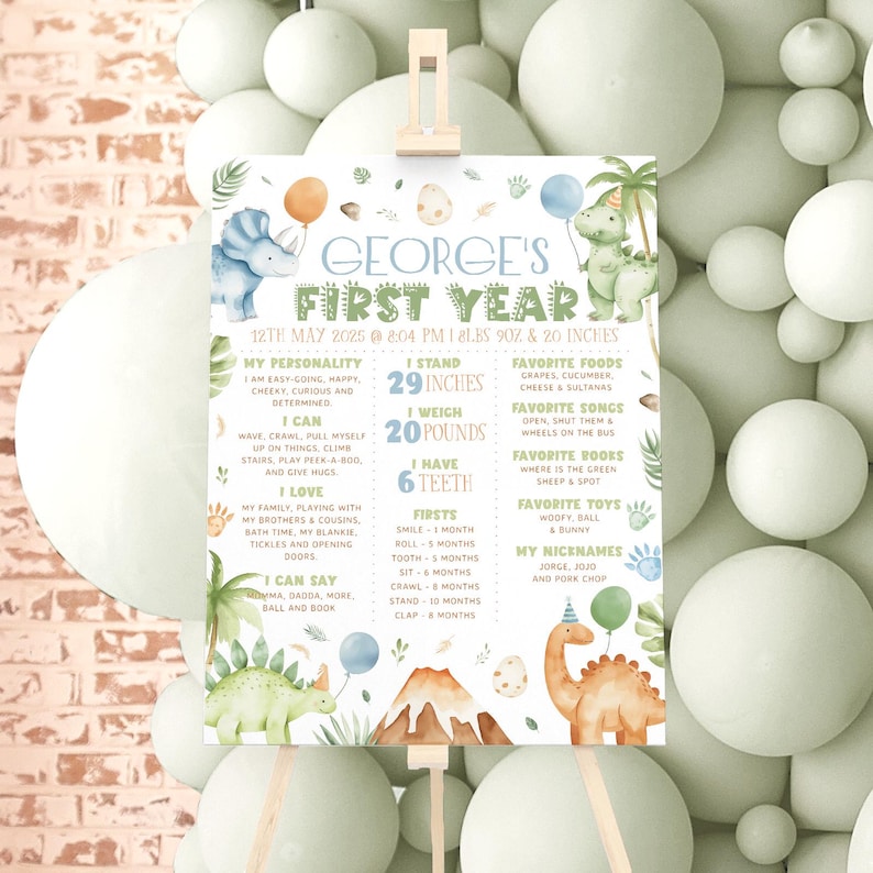 May include: A green and blue dinosaur-themed first birthday chart for a baby named George. The chart lists his age, height, weight, and other milestones. It includes a cute dinosaur illustration.