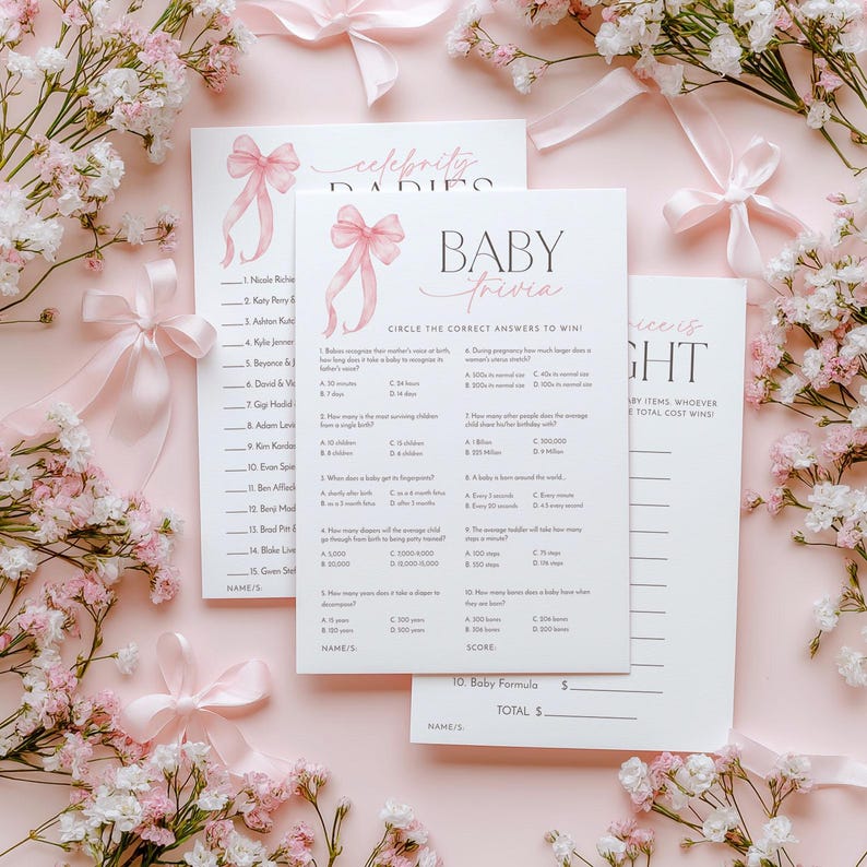 K&ouml;nnte beinhalten: Rosa und wei&szlig;e Babyparty-Spielkarten mit einem rosafarbenen Schleifendesign. Die Karten beinhalten ein Baby-Quizspiel und ein Spiel mit Promi-Babys. Der Text auf den Karten lautet "Baby Trivia" und "Celebrity Babies".