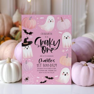 May include: Pink invitation with a ghost wearing a witch hat and the text "Charlotte is a Spooky One". The invitation also features pumpkins, bats, and candy. The text "Join us to celebrate Charlotte's 1st Boo-Day!" is also included.