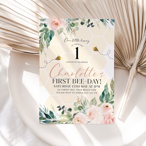May include: An invitation card with a floral design and the text "Charlotte's First Bee-Day!" features a honeycomb background, watercolor roses, and greenery. The design includes a bee graphic and the words "Our little honey is turning 1."
